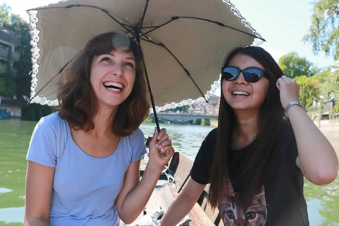 2 students with a parasol on a boat