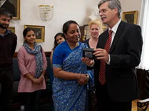 Rektor Prof. Dr. Bernd Engler überreicht der indischen Botschafterin Sujatha Singh eine Replike des 35.000 Jahre alten Elfenbein-Mammuts vom Hohle Fels auf der Schwäbischen Alb. In der Mitte Prof. Dr. Susanne Marschall vom Institut für Medienwissenscha