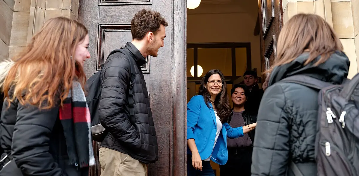 Studierende stehen vor einer Tür und werden freundlich begrüßt