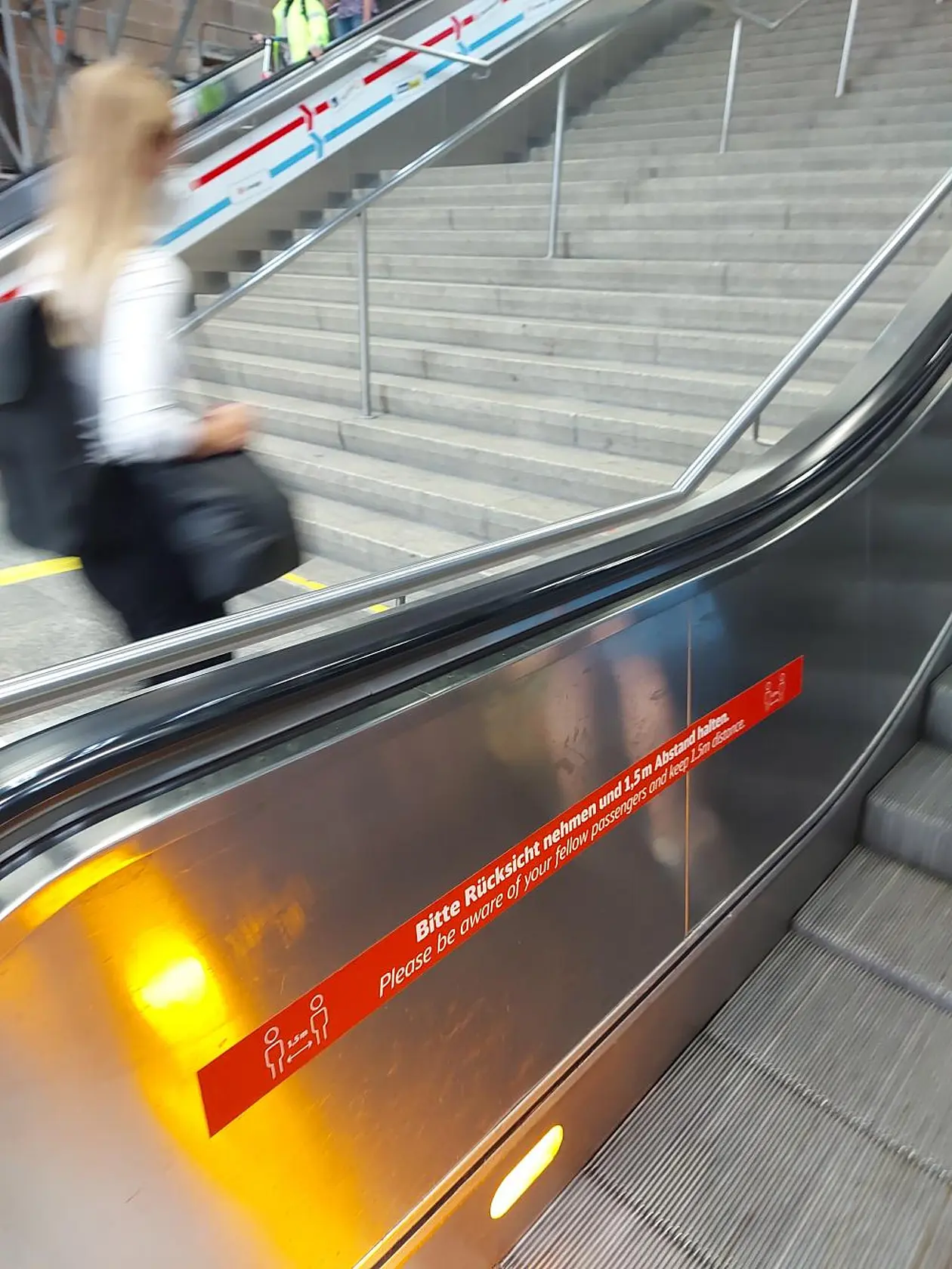 Eine Rolltreppe mit vorbeilaufender Person.