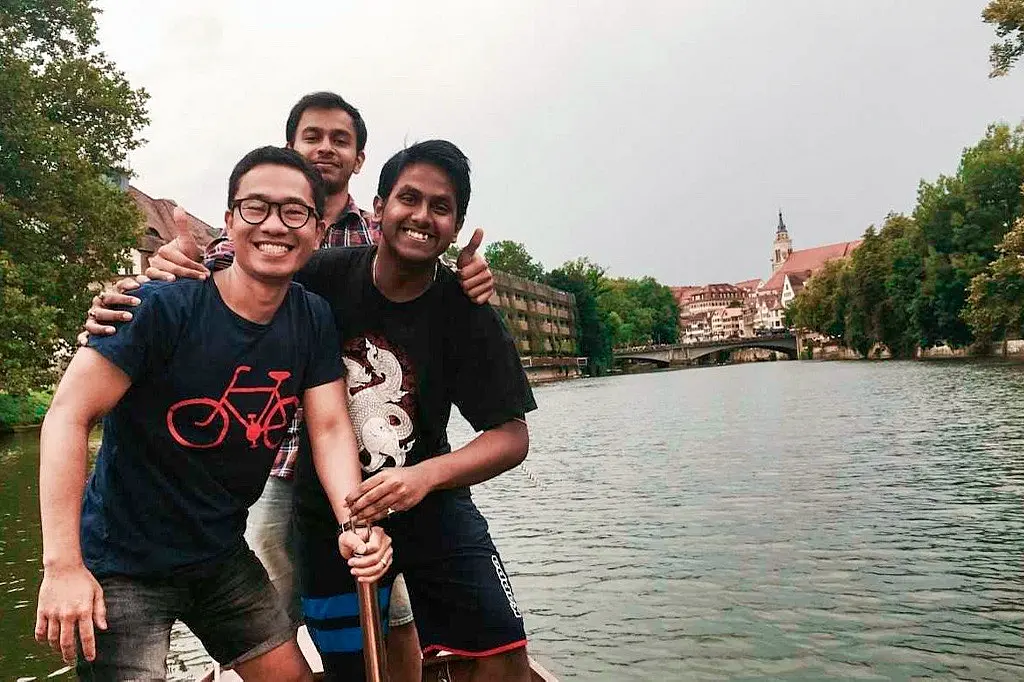 Three students posing for a picture while standing on a boat on the Neckar
