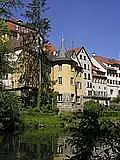 rechts ist ein rechter Baum, mittig ein gelber Turm, allgemein hat man Blick auf die historische Altstadt Tübingens
