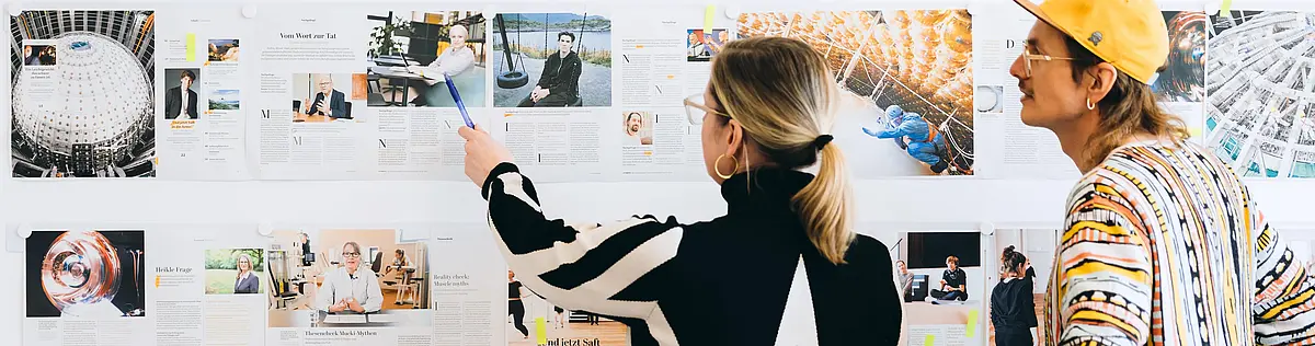 A woman and a man are looking at photos hanging on a wall.