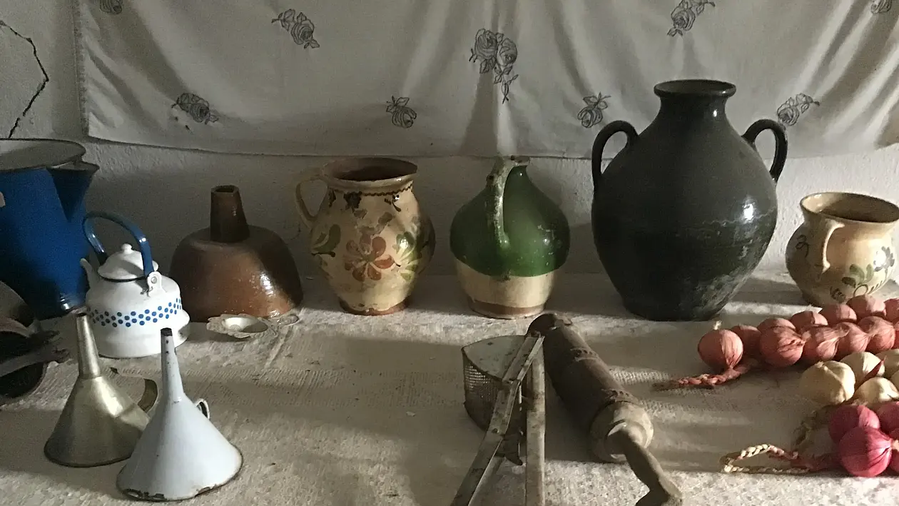 Dekoratives Bild von alten Alltagsgegenständen wie Vasen, Trichter und Zwiebeln auf einem Tisch.