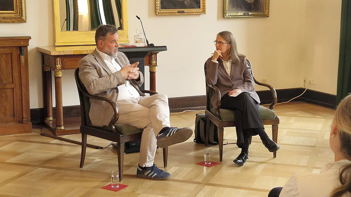 Rolf Frankenberger und Monique Scheer sitzen auf zwei Stühlen und sprechen miteinander