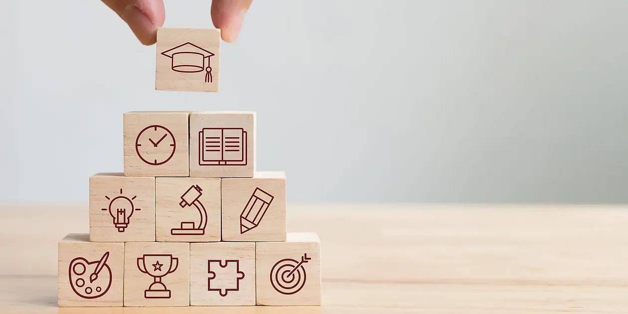 Image of wooden cubes with symbols representing competencies that can be acquired in the Graduate Academy's offer.