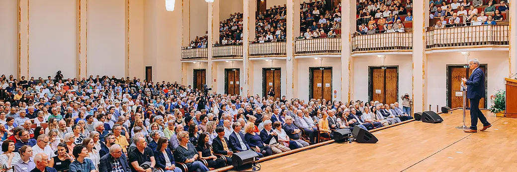 Ein Mann spricht vor einem vollen Saal