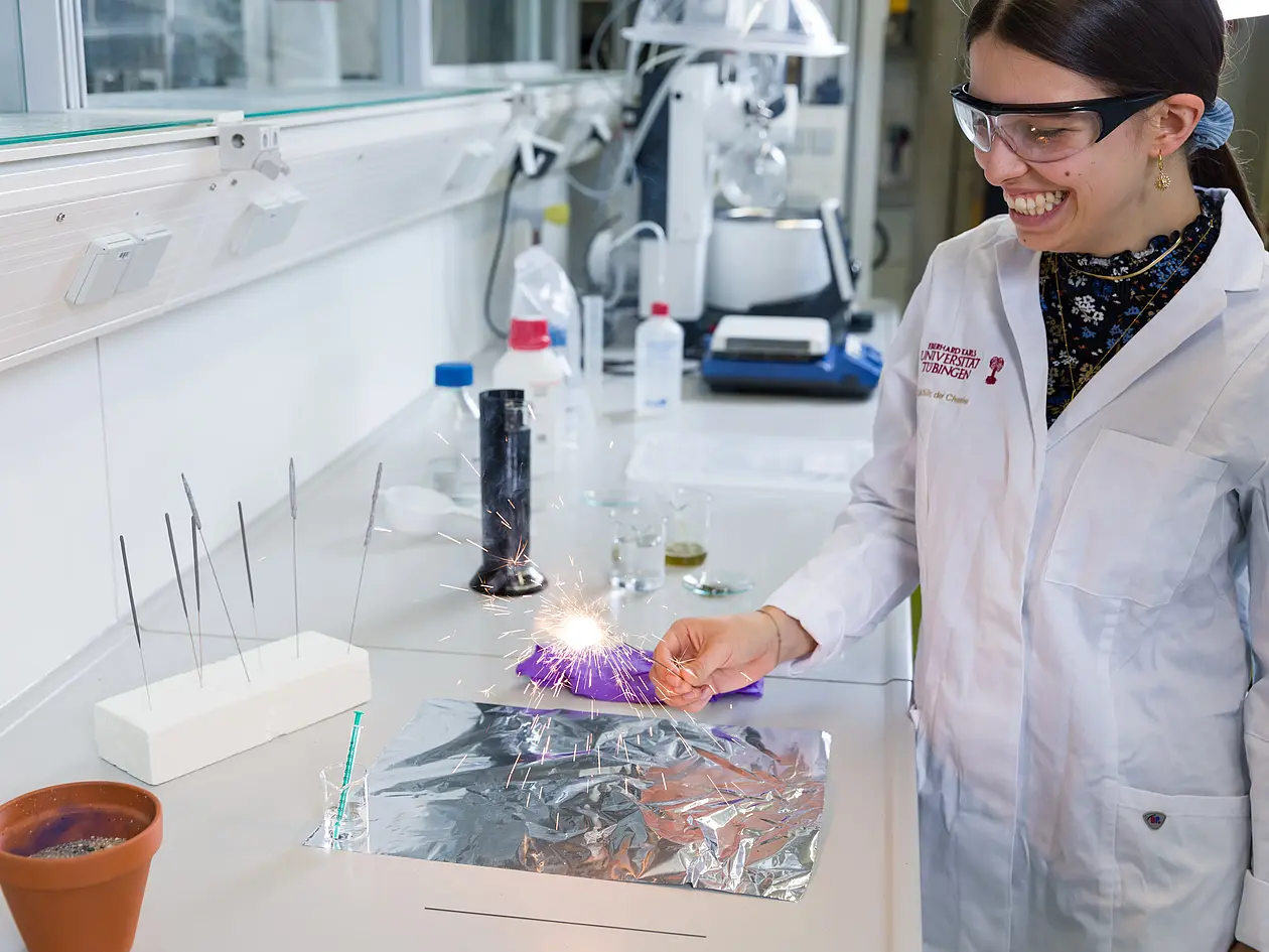 Foto einer Studentin die Praktikanten einen Versuch im Labor vorführt