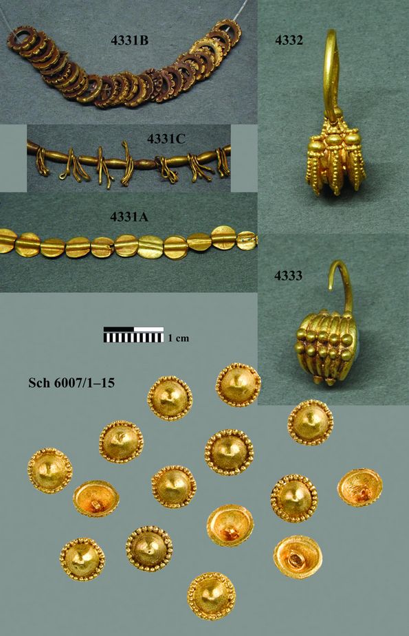Photo of various gold objects, including three necklaces, a pair of earrings and several brooches