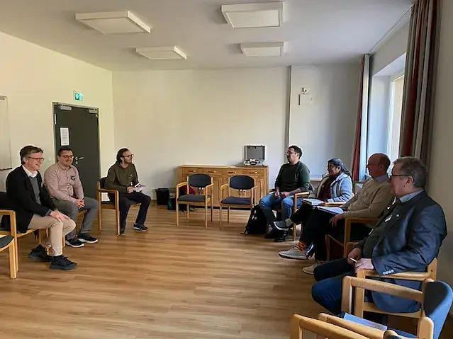 Auf dem Bild sind insgesamt sieben Personen unterschiedlichen Alters zu sehen, die in einem Halbkreis sitzen. Am linken Ende des Halbkreises sitzt Prof. Winter. Unter der sieben Personen befindet sich eine Frau - etwa im rechten Drittel des Halbkreises.