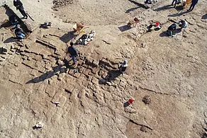 ArchäologInnen und Arbeiter legen Lehmziegelmauern der Gebäude in der alten Stadtanlage von Kemune frei 