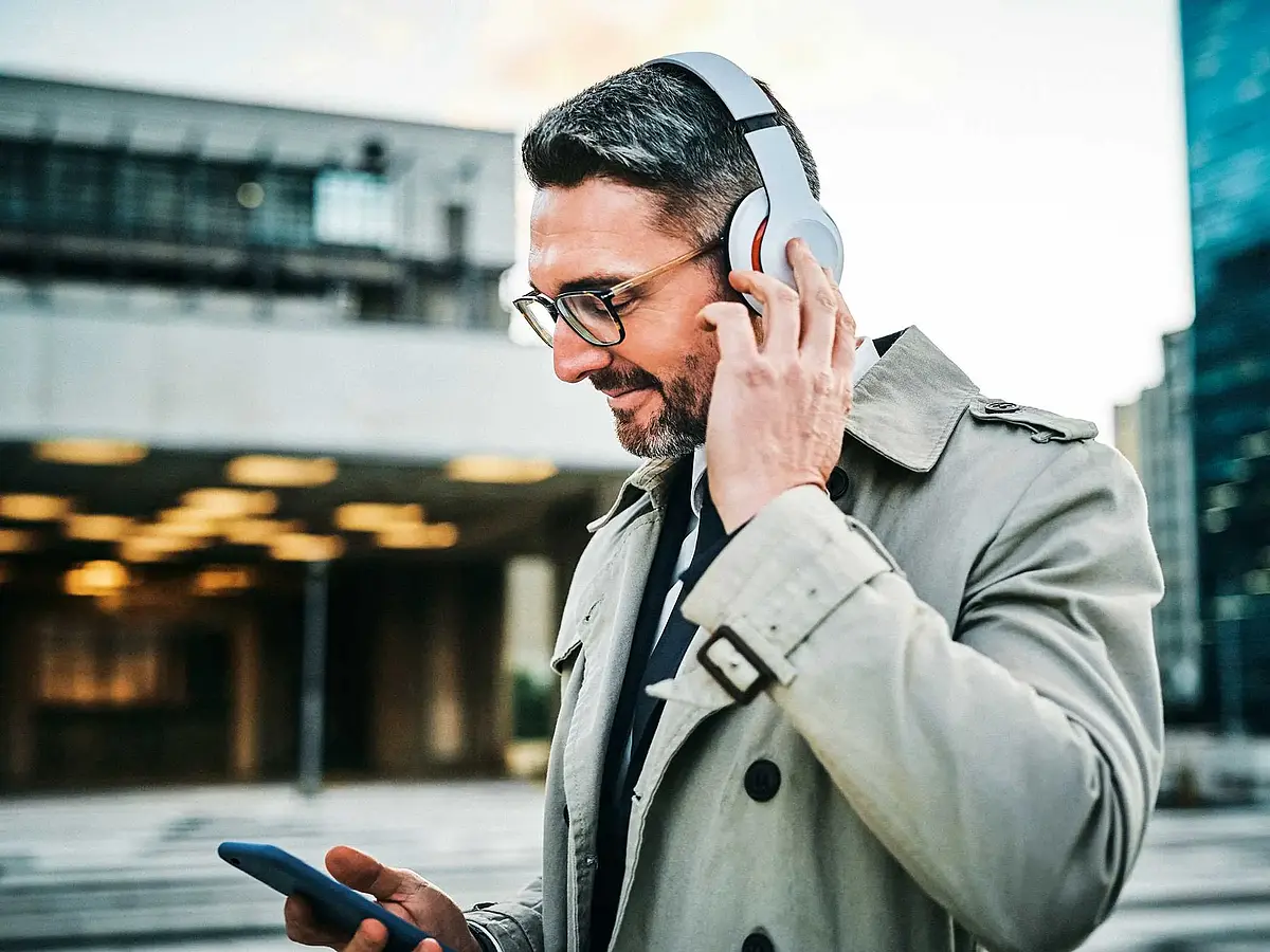 A man holding a cell phone and wearing headphones.