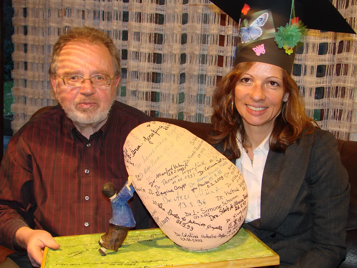 Professor Dr. Wolf Engels sitzt neben Regina Grupp, die ihre Promotion 2009 beendete. Vor den beiden steht das „Engels’sche Ei“ mit den Unterschriften.