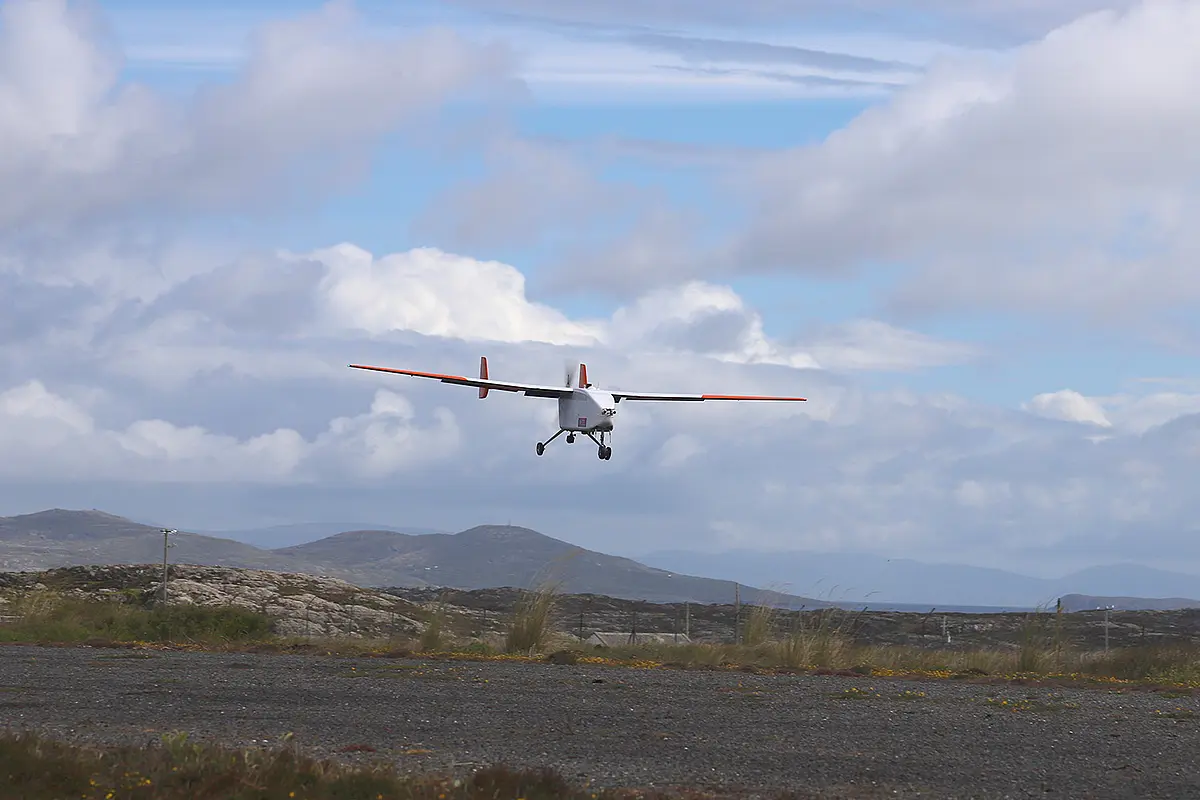 Kleines Flugzeug über Schotterplatz in grüner Hügellandschaft