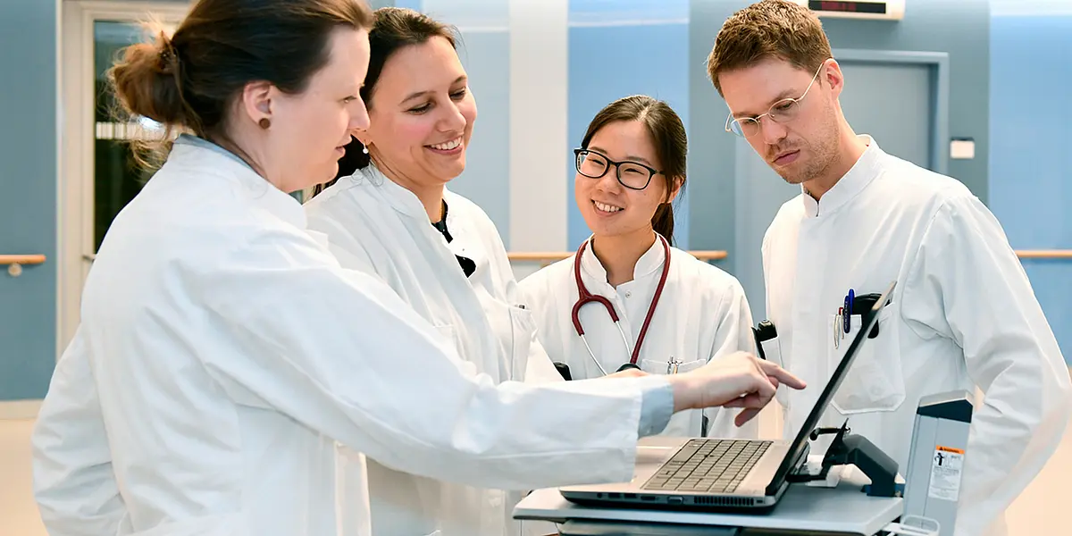 Junge Medizinerinnen und Mediziner in einer Klinik, sie betrachten einen Bildschirm.