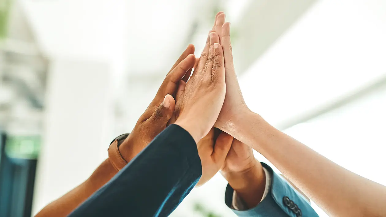 Hände verschiedener Personen die sich in der Luft ein Highfive geben 