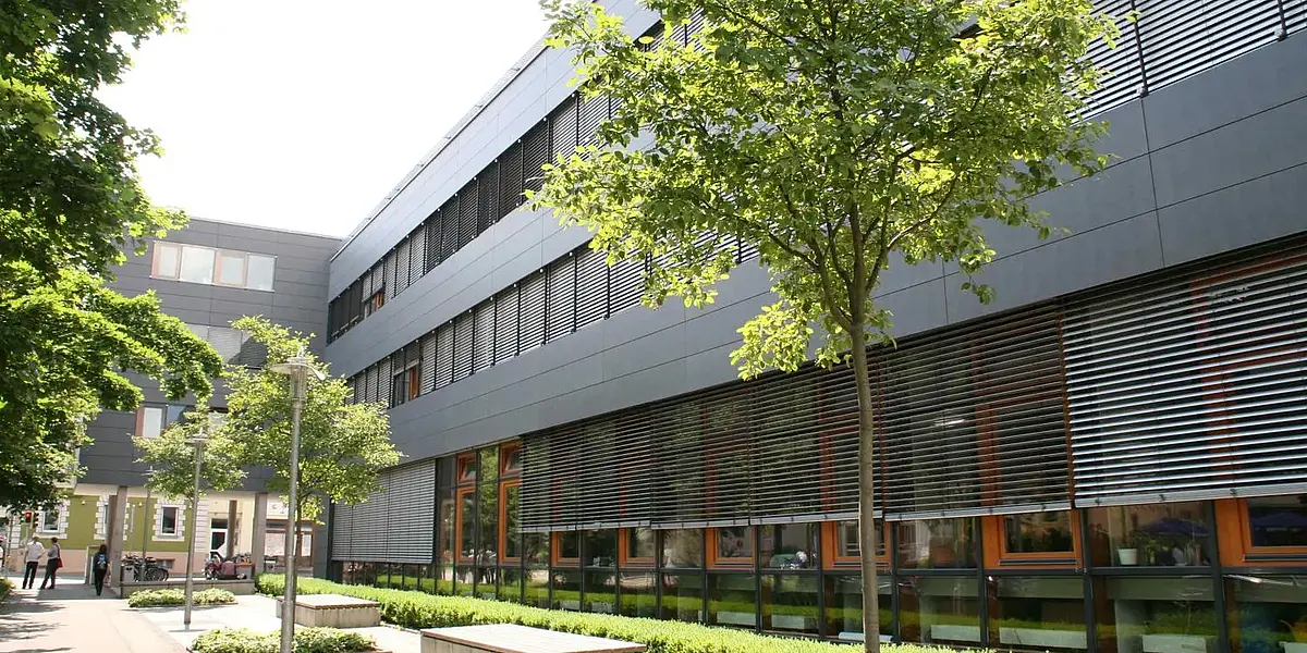 Outside view of a modern building with trees and benches in front