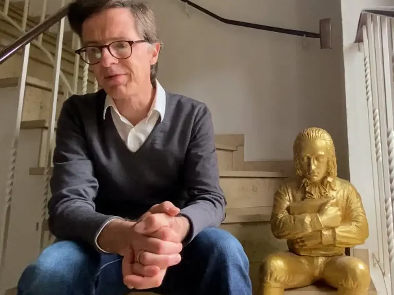 Stephan Winter mit einer goldenen Hölderlinfigur auf einer Treppe