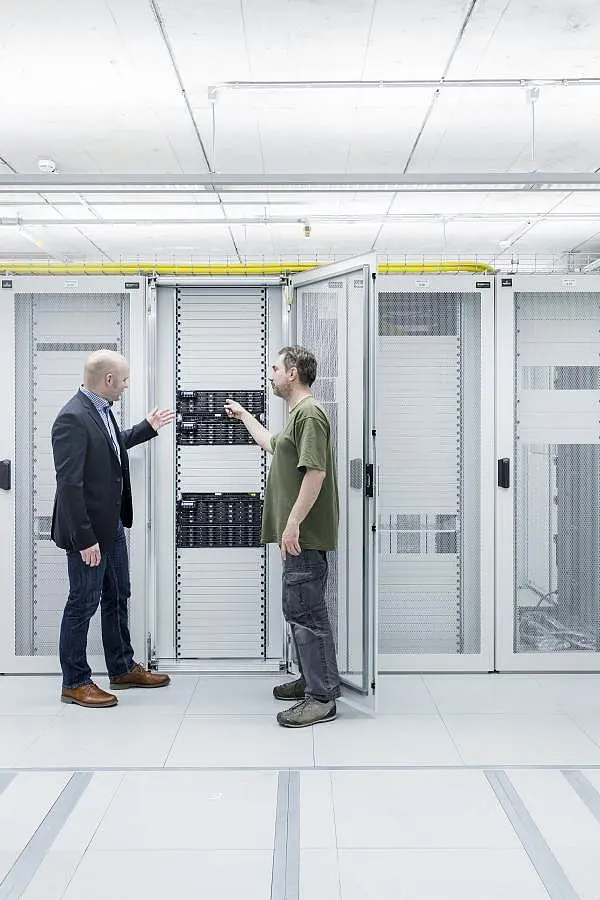 Zwei Wissenschaftler besprechen sich vor einem Rechencluster des QBiC.
