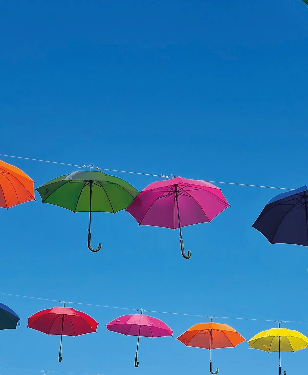 Bunten Regenschirme, die nebeneinander im blauen Himmel schweben. 