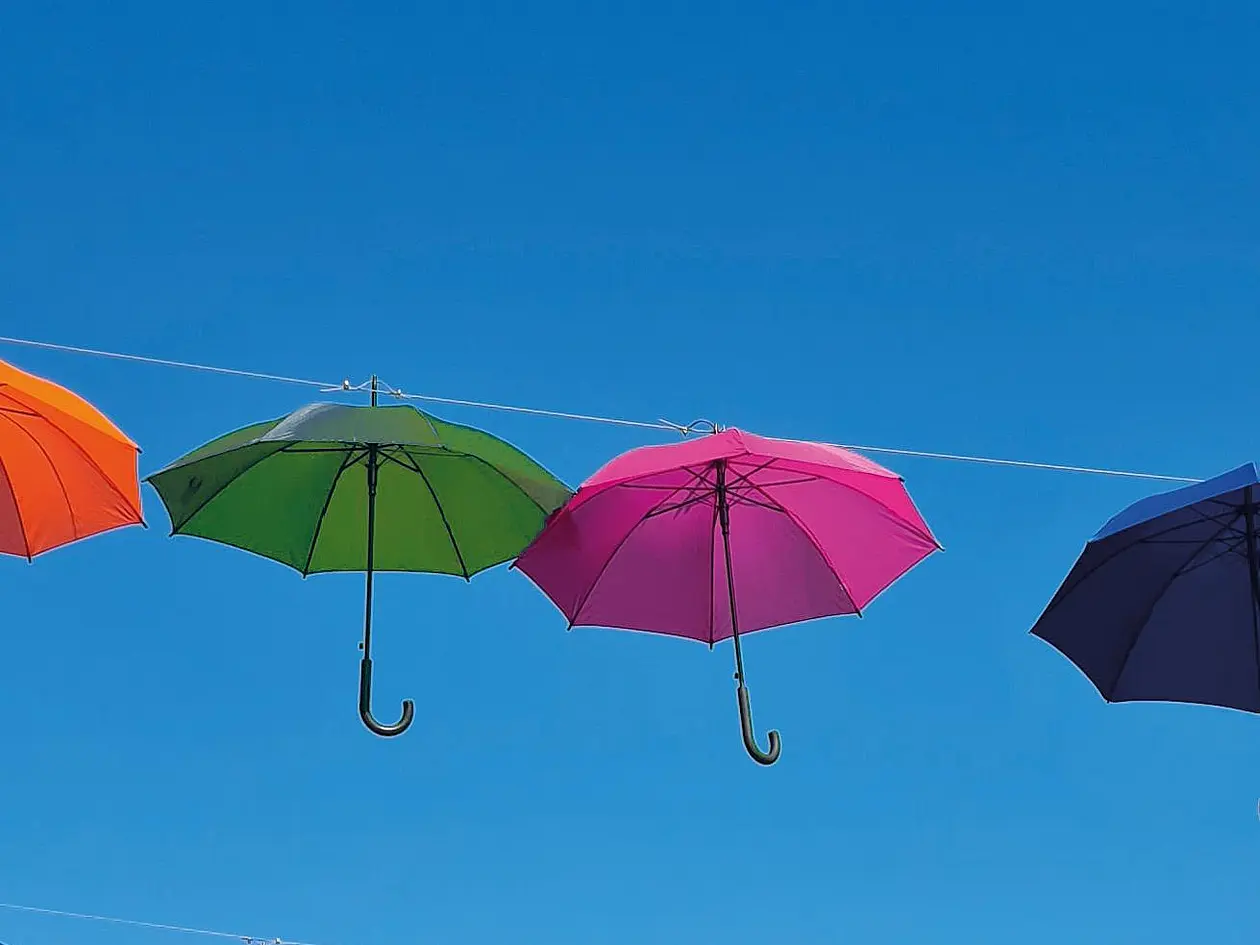Bunten Regenschirme, die nebeneinander im blauen Himmel schweben. 