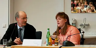 Hans-Peter Thier und seine Patientin Marina Stüber sitzen an einem Tisch