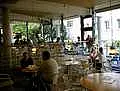 Innenraum der Cafeteria. Menschen sitzen an verschiedenen Tischen.