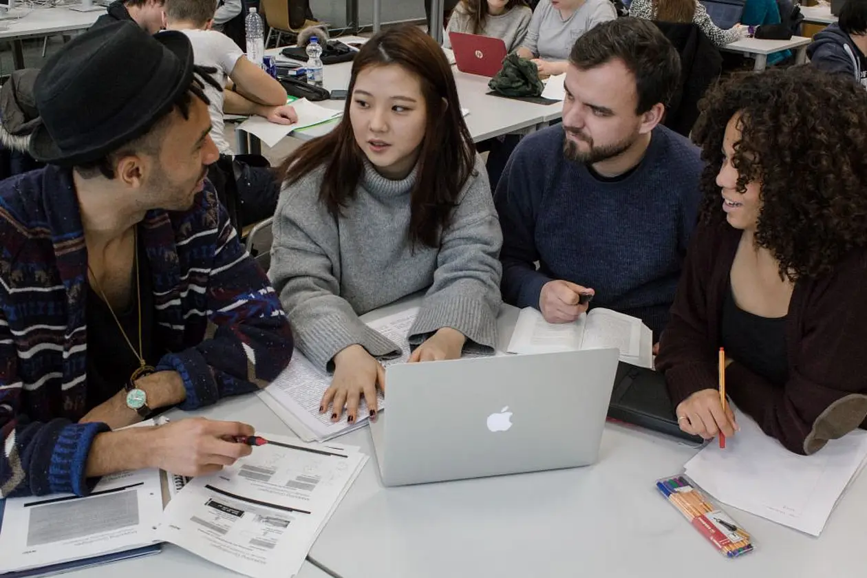 Studierende diskutieren im Seminarraum eine Gruppenarbeit