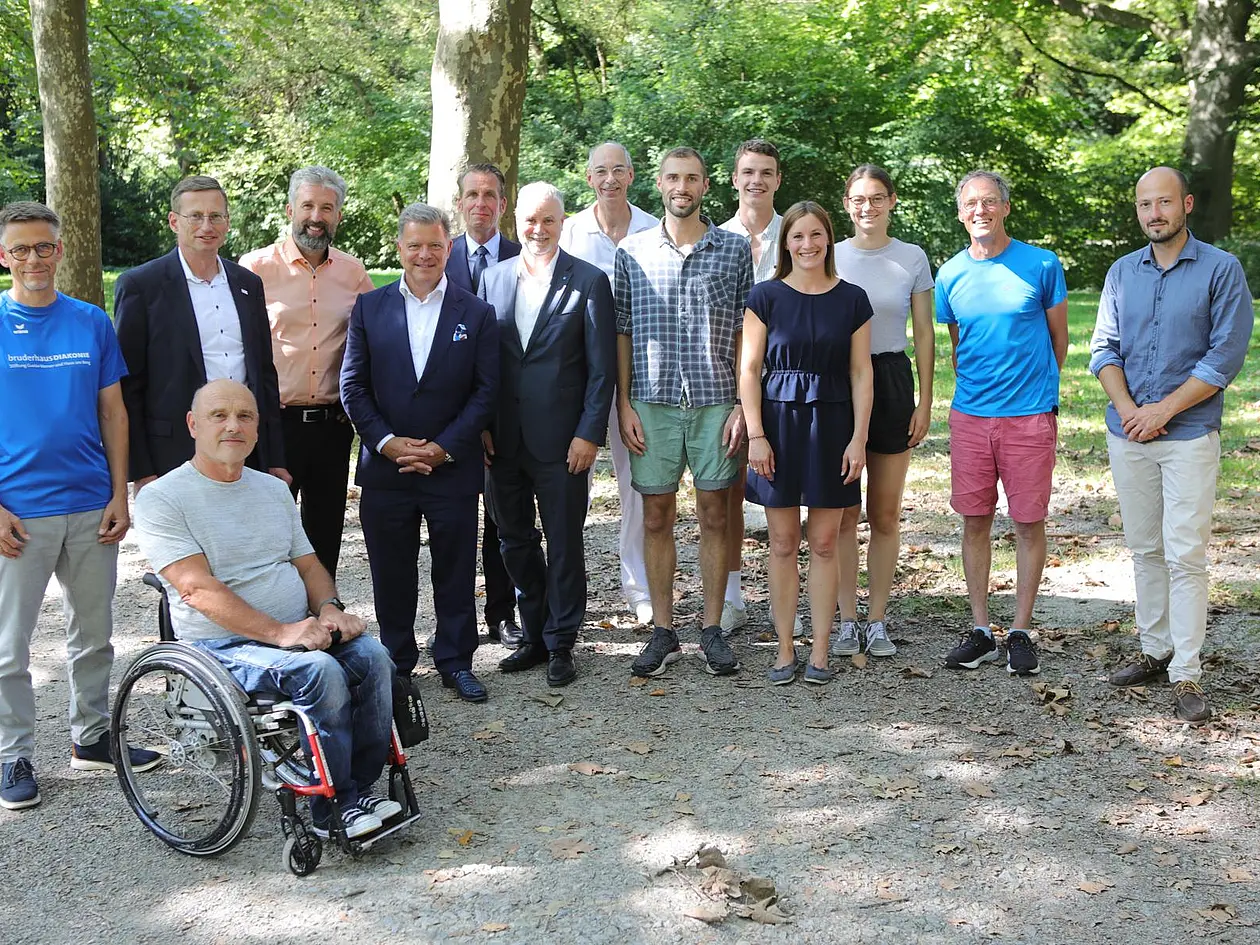 Foto einer Gruppe Menschen, einer sitzt im Rollstuhl