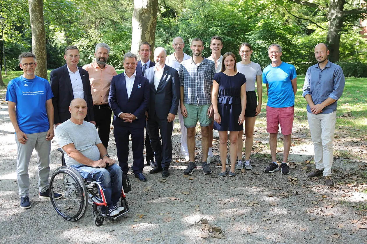 Foto einer Gruppe Menschen, einer sitzt im Rollstuhl