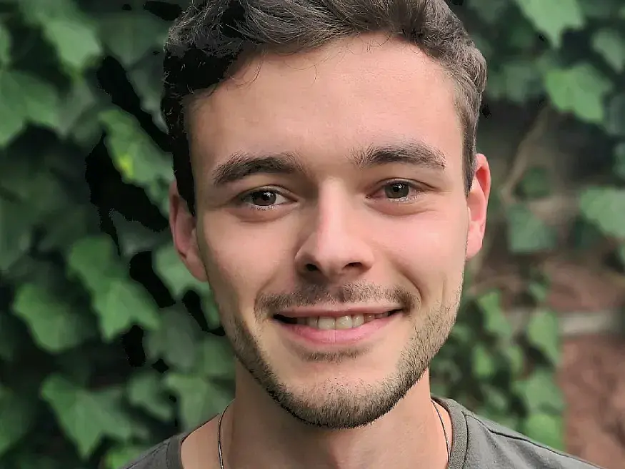 The photography shows a head shot of Moritz Adam smiling into the camera.