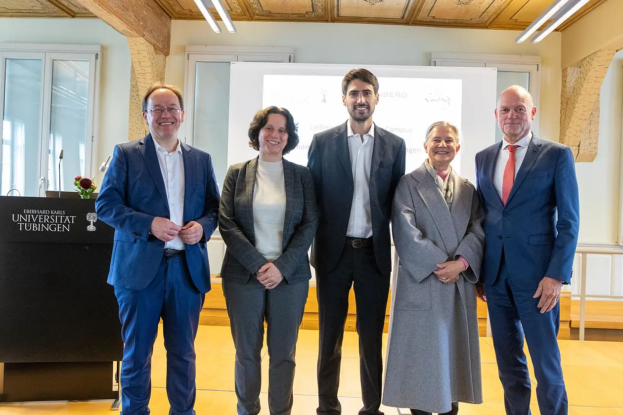Gruppenfoto der Rednerinnen und Redner neben Pult mit Logo der Universität Tübingen
