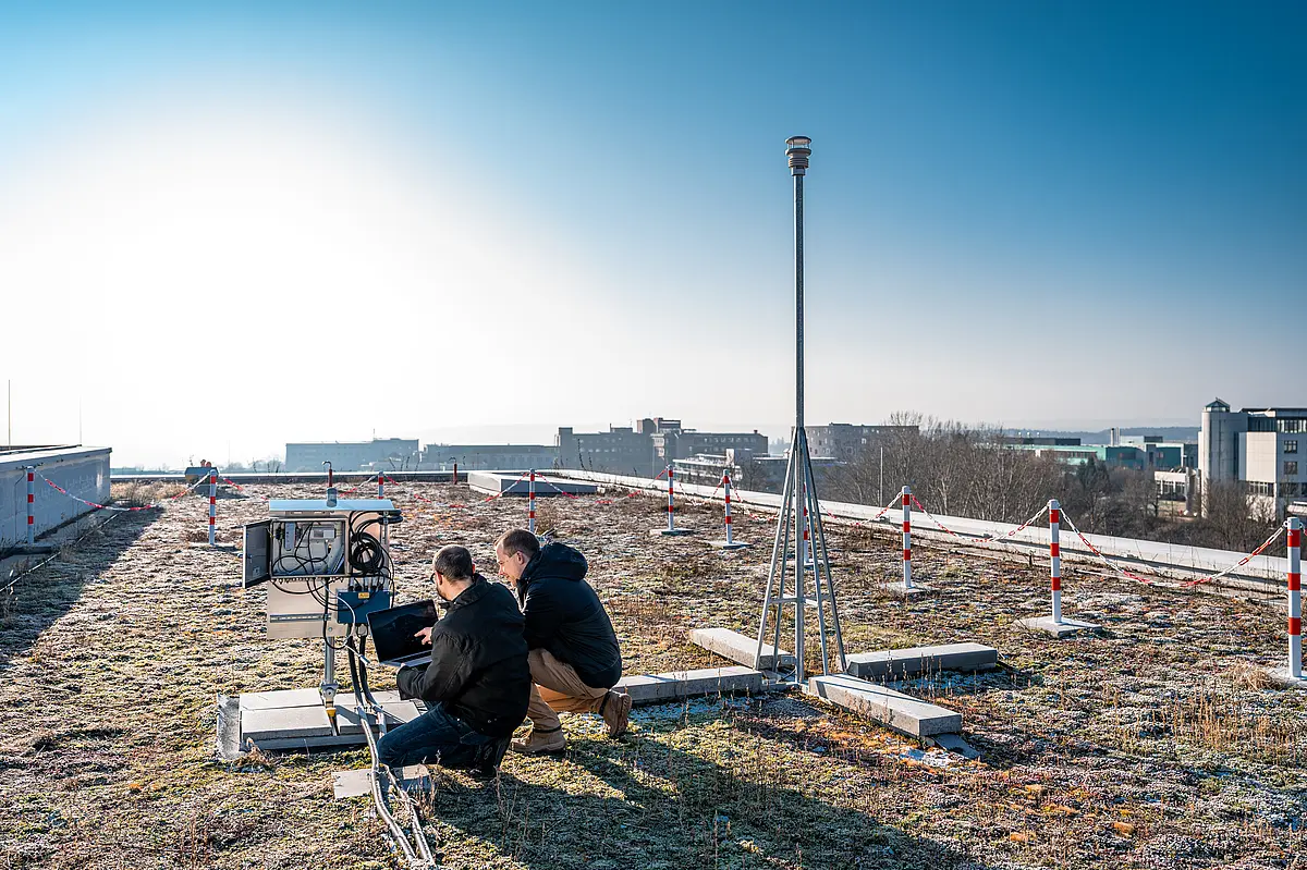 Zwei Forschende an der Wetterstation auf dem begrünten Dach des Geo- und Umweltforschungszentrums Tübingen.