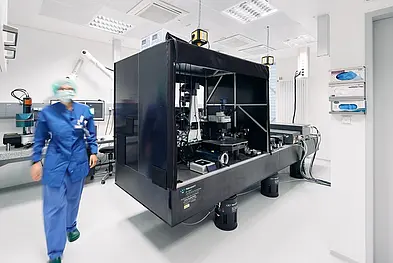 A multiphoton intravital microscope. In front of it a scientist walking towards the camera.