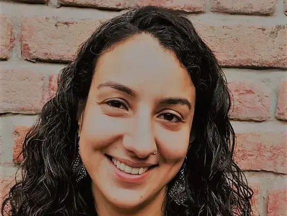 A woman in her early 30s with dark curly shoulder length hair