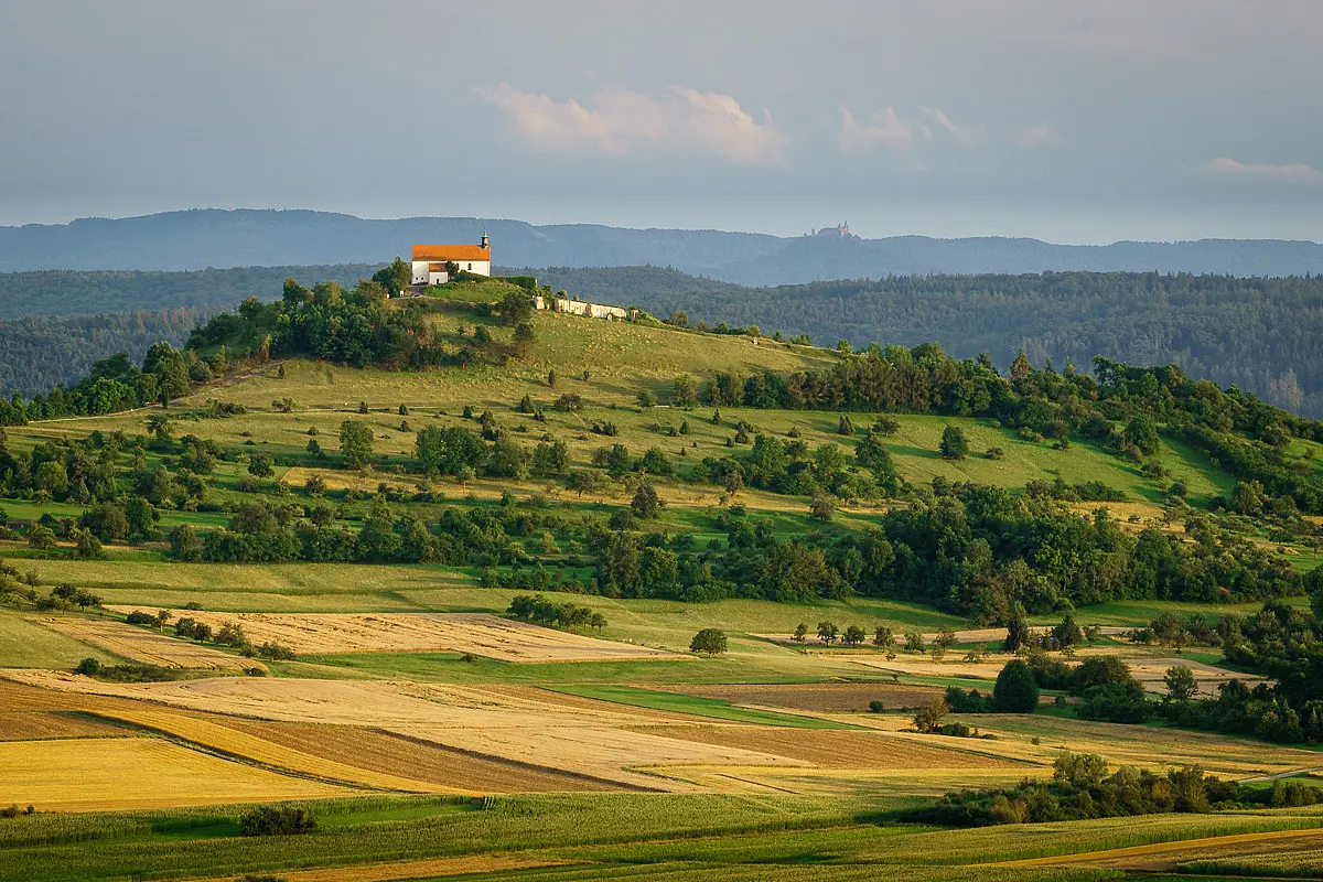 Felder und Wiesen und die Wurmlinger Kapelle, im Hintergrund die Schwäbische Alb