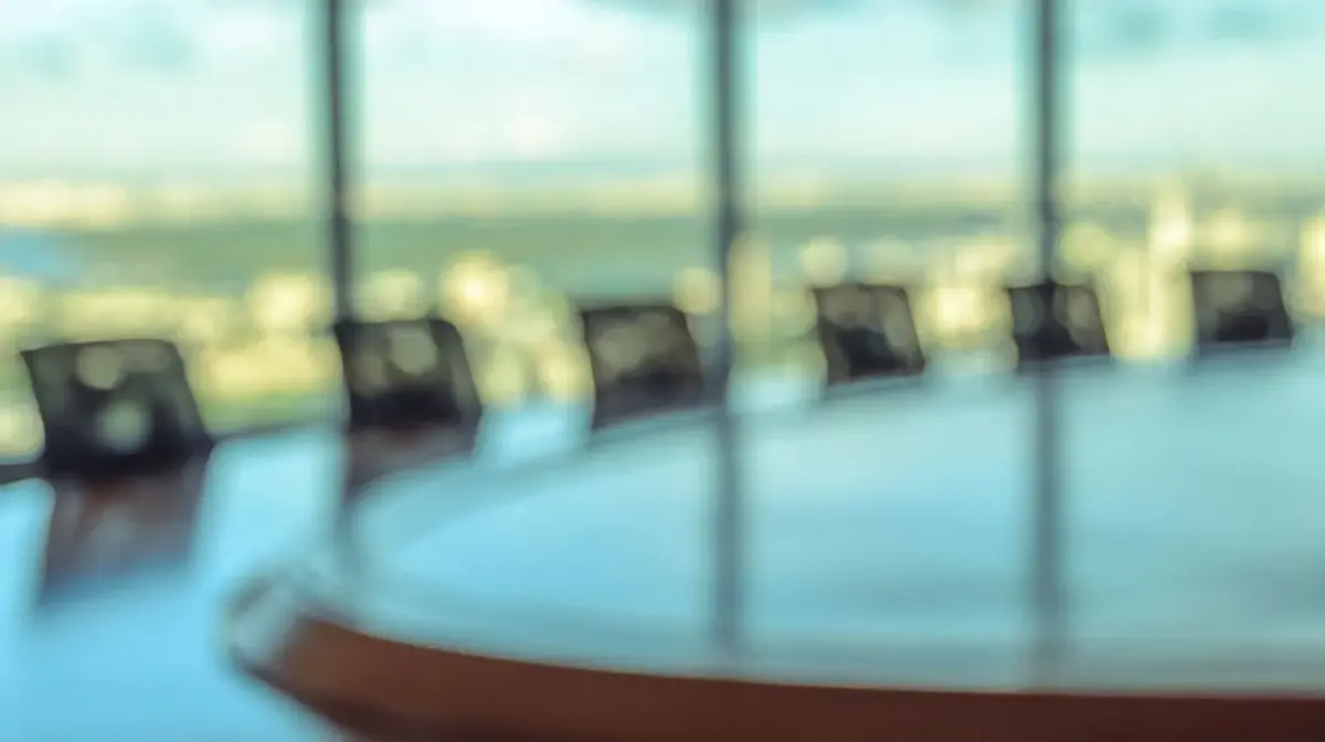 Round conference table with six empty chairs.