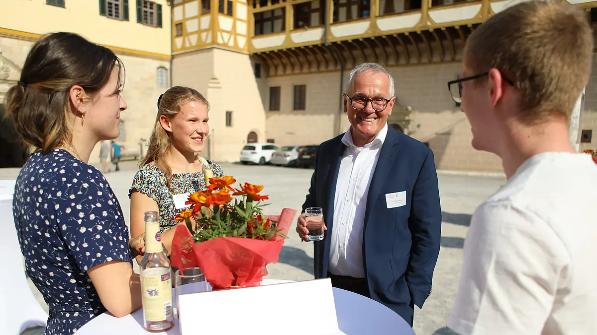 Ein Fördernder unterhält sich mit Studierenden. 