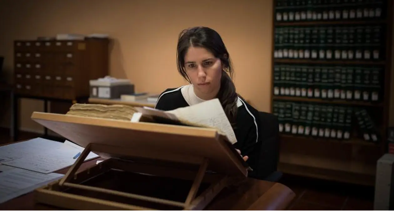 Laura Dierksmeier sits at a desk reading a historical book 