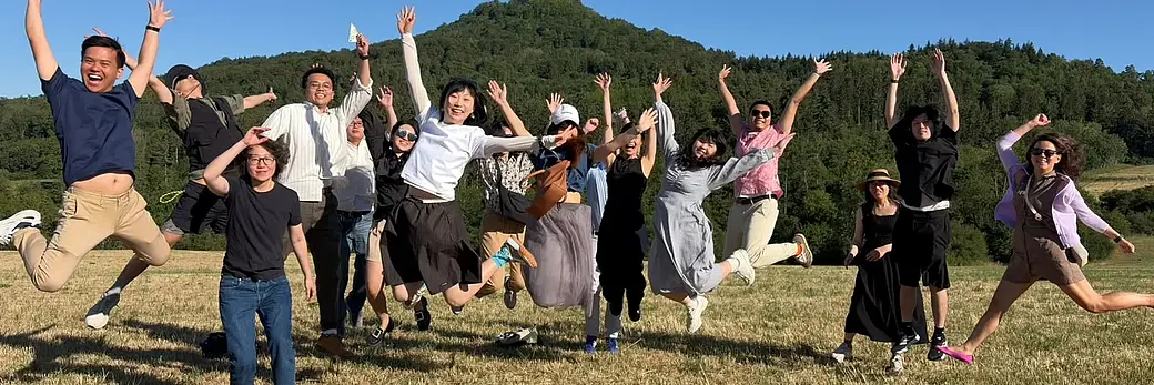 Young Asian People cheerfully jumping into the air against the background of Hohenzollern Castle.