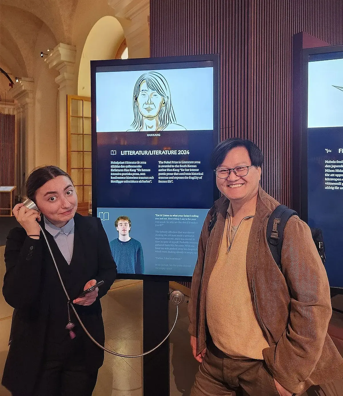 Professor You Jae Lee and a student are standing in front of an infoscreen in the Nobel Prize Museum in Stockholm