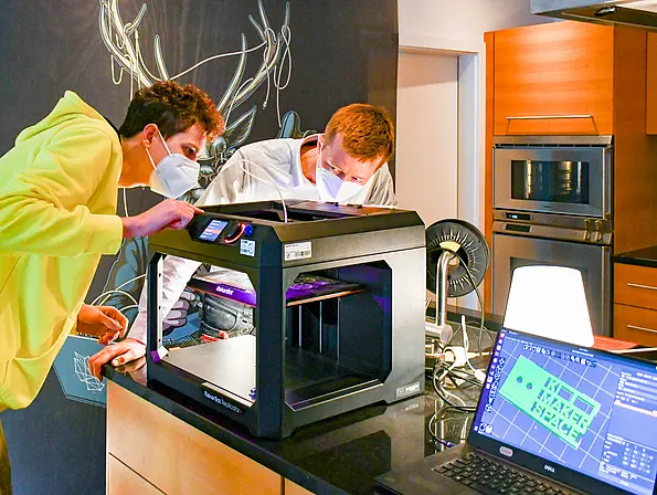 Ein Schüler und ein Wissenschaftler arbeiten an einem 3-D-Drucker