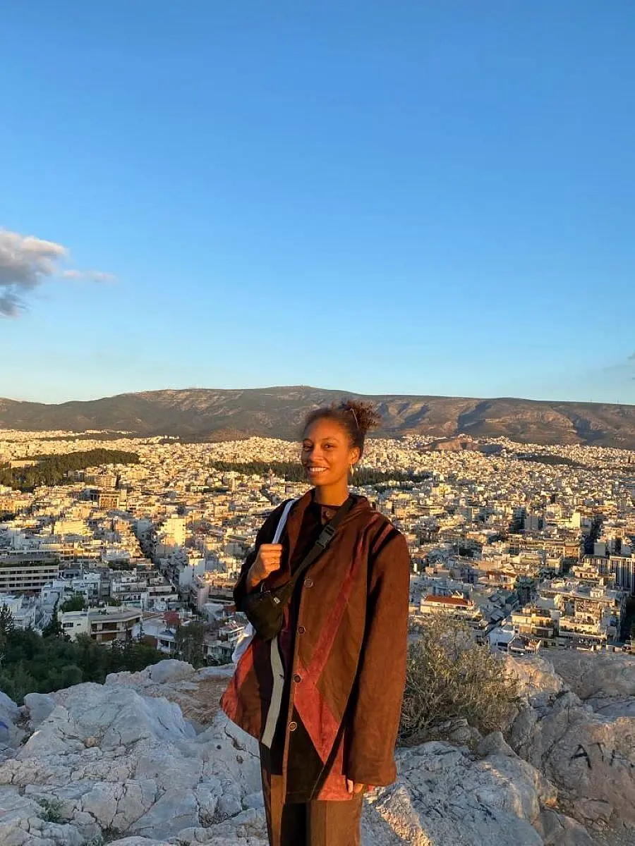 Alicia Ogwumika auf einem Berg, im Hintergrund Athen von oben