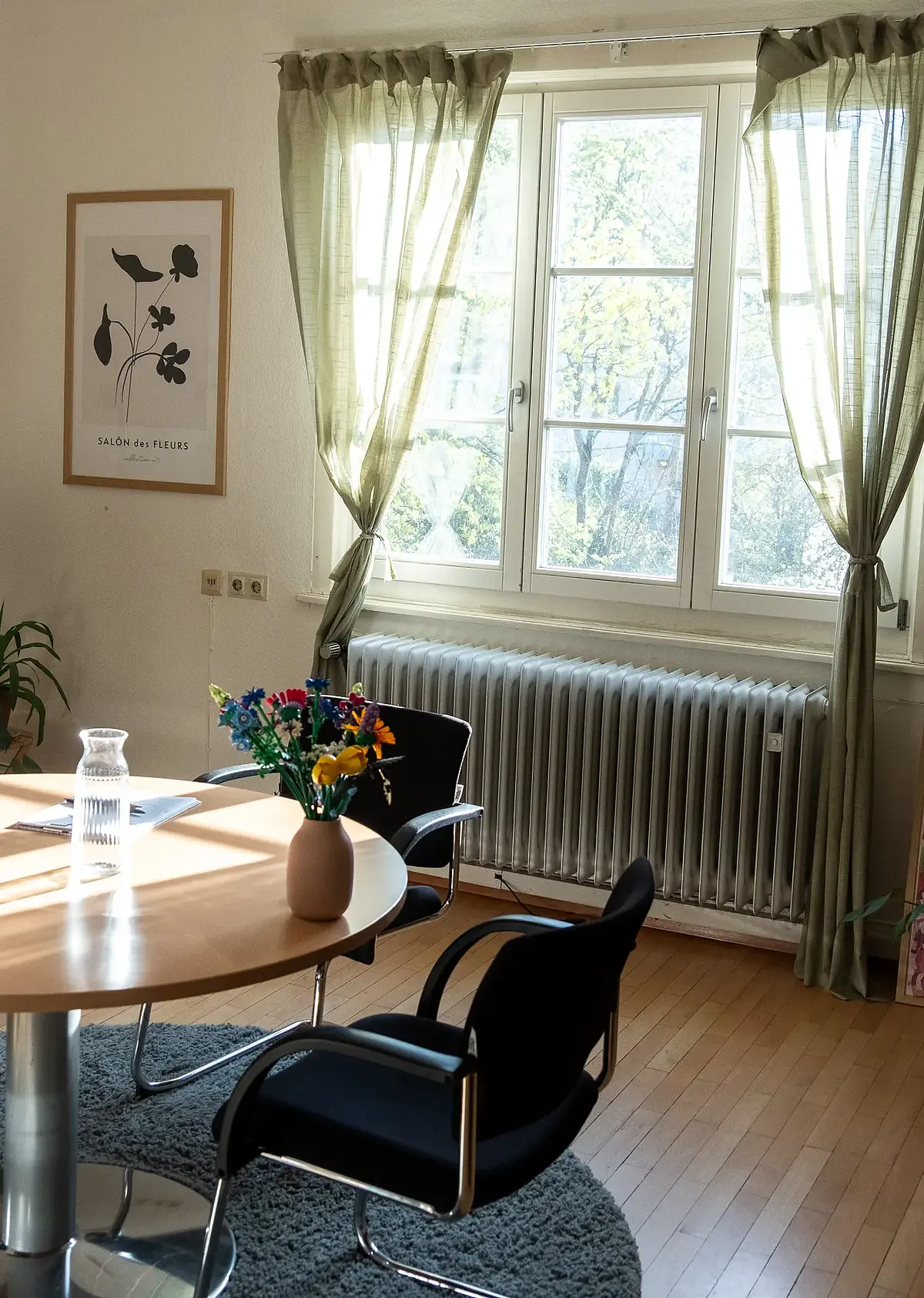 Therapiezimmer der Psychotherapeutischen Hochschulambulanz Tübingen mit großem Fenster, Tisch und zwei Stühlen.