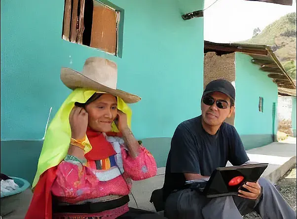 A man in his early 40s with a baseball cap and sunglasses sitting next to an indigenous woman