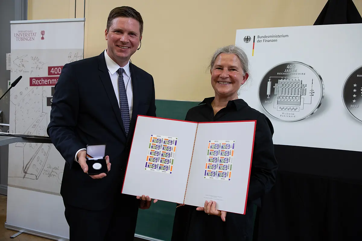 Florian Toncar zeigt eine Münze im Schmuckkasten, Karla Pollmann zwei Bögen mit Sondermarken