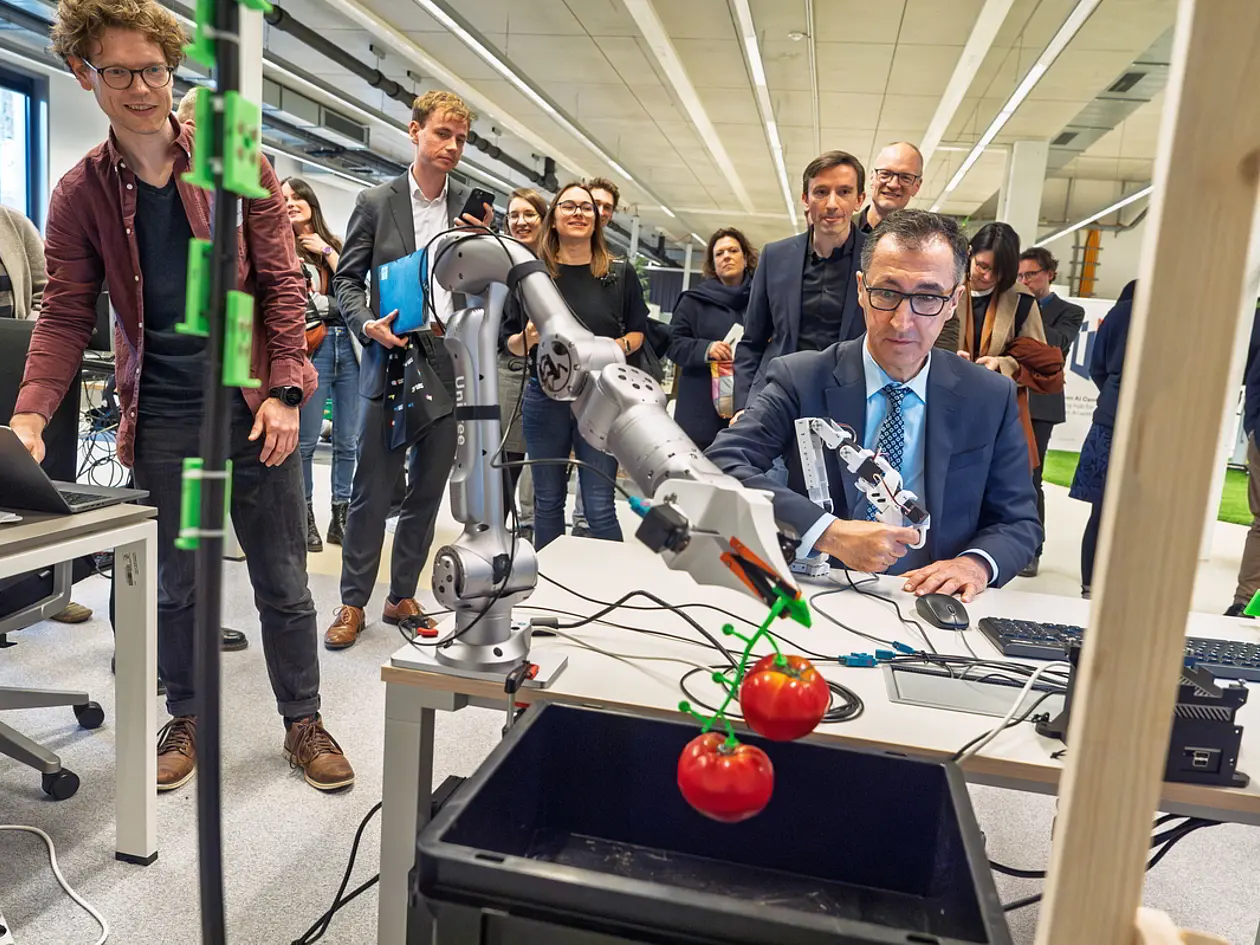 Bundesforschungsminister Cem Özdemir beim Besuch am Tübingen AI Center: Der Minister steuert den Arm des Ernteroboters Polybot, der für die Tomatenernte trainiert wird.