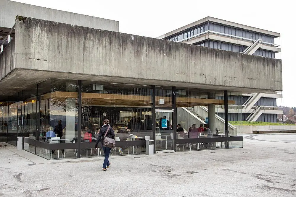 Blick von außen auf die Cafeteria im Hörsaalzentrum Morgenstelle. Durch die Glasfront sind Studierende im Innenraum erkennbar.