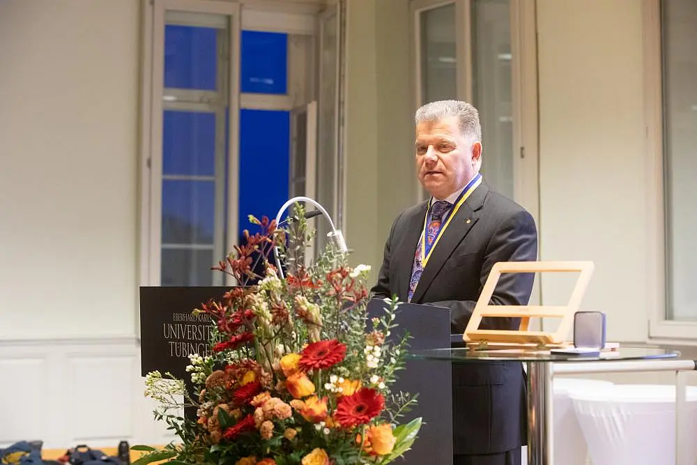 Christian O. Erbe am Redepult. Im Vordergrund ein festlicher Blumenstrauß.