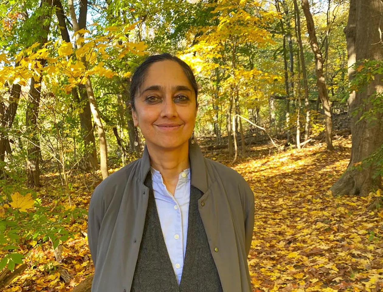 Photo of professor Leela Gandhi standing in autumn forest